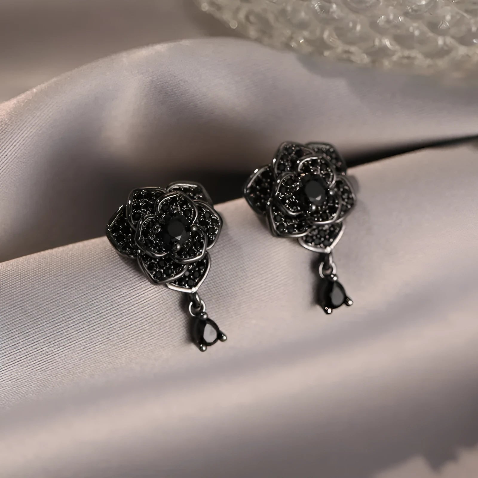 Black rose zircon inlaid stud earrings with 18K gold plated copper flower shape on white background