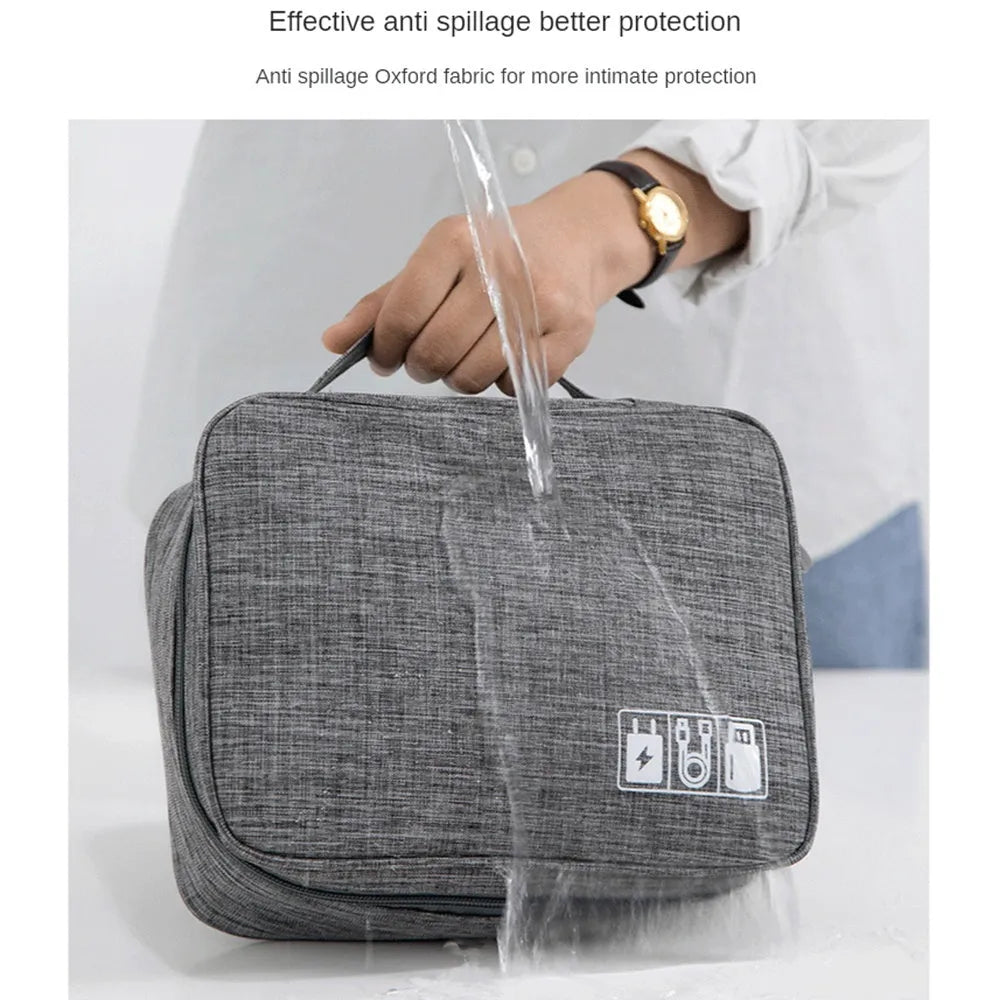 Black electronics organiser case open to show mesh pockets, elastic loops and removable padded dividers inside.