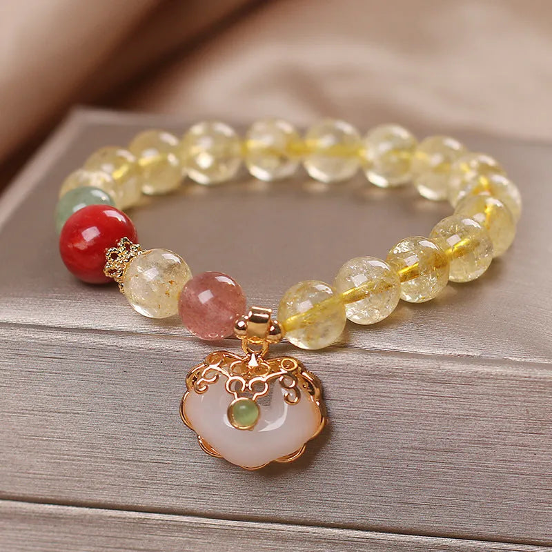 Close-up of a women's adjustable bracelet with a yellow citrine jade ruyi pendant on an alloy chain.