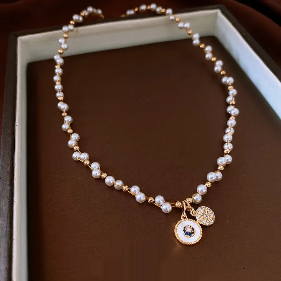 Gold electroplated round pendant necklace with zircon pearl on an adjustable clavicle chain.