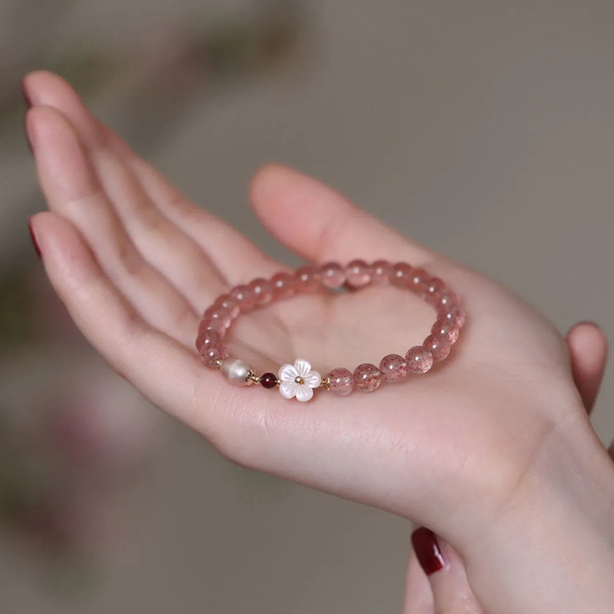 Women's strawberry quartz crystal bracelet with flower-shaped peach blossom design on wrist