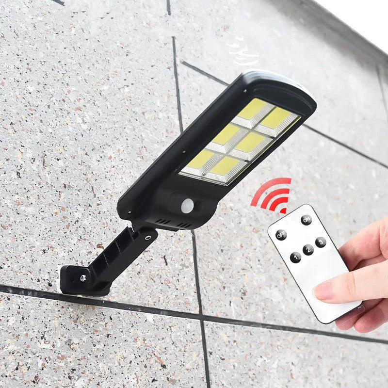 Black outdoor solar-powered motion sensor light mounted on a wall with solar panel visible.