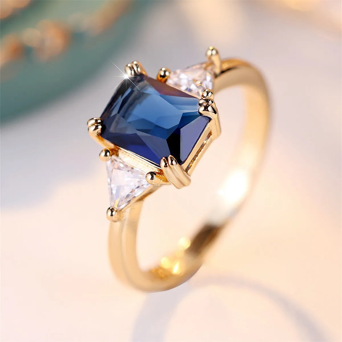 Ladies rectangular copper fashion ring in gold sapphire blue finish on finger