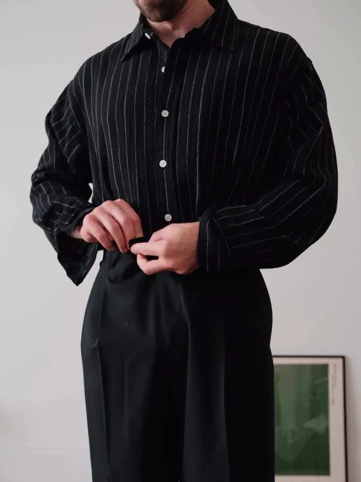 Man wearing a black pinstriped button-down long sleeve shirt with a collar.