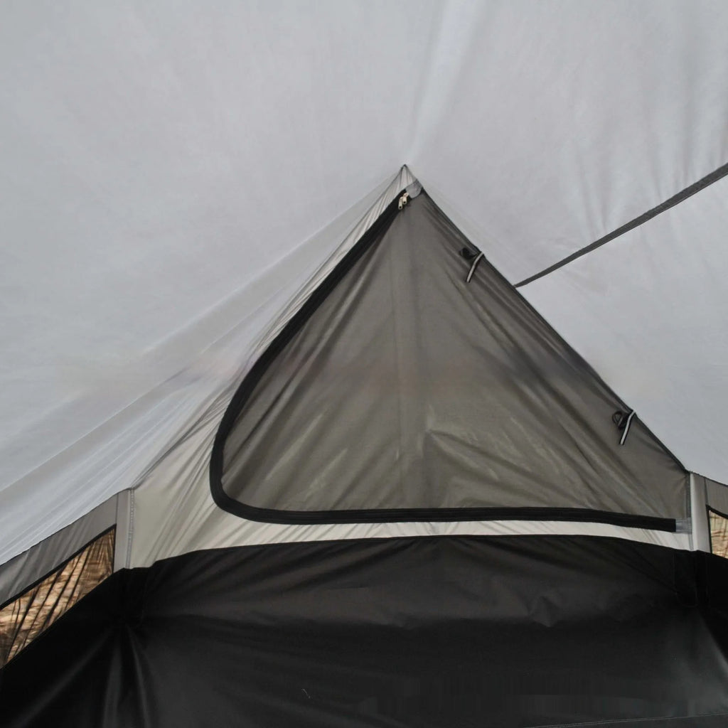 Brown A-line hiking tent set up with trekking poles in a forest clearing.