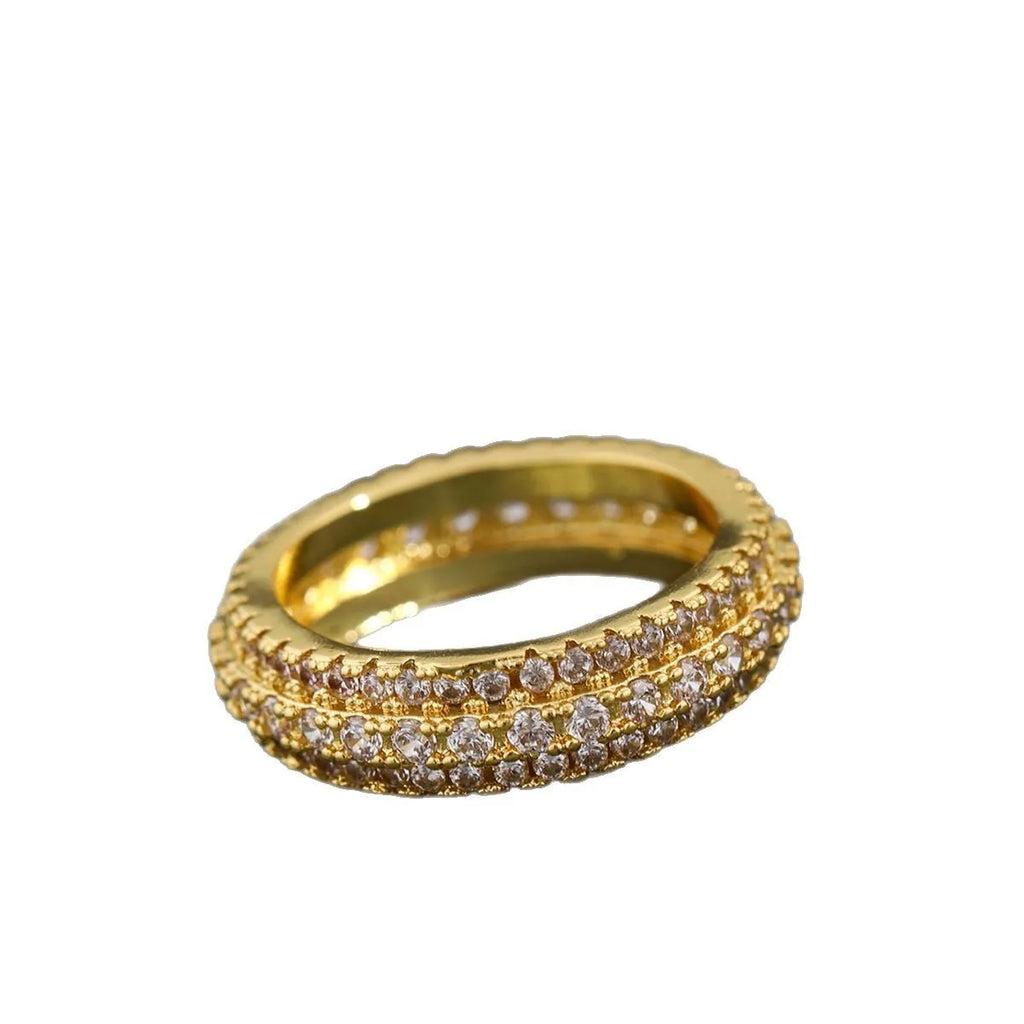 Geometric triangle personalised zircon ring in yellow gold on a grey background.