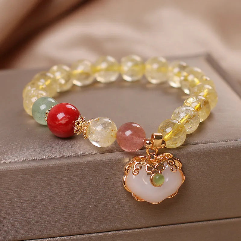 Close-up of a women's adjustable bracelet with a yellow citrine jade ruyi pendant on an alloy chain.