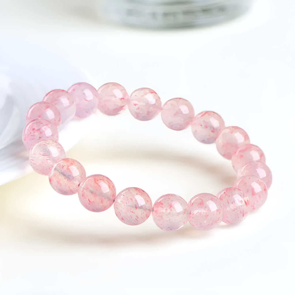Strawberry quartz crystal bracelet with white geometric beads on a stretch band.
