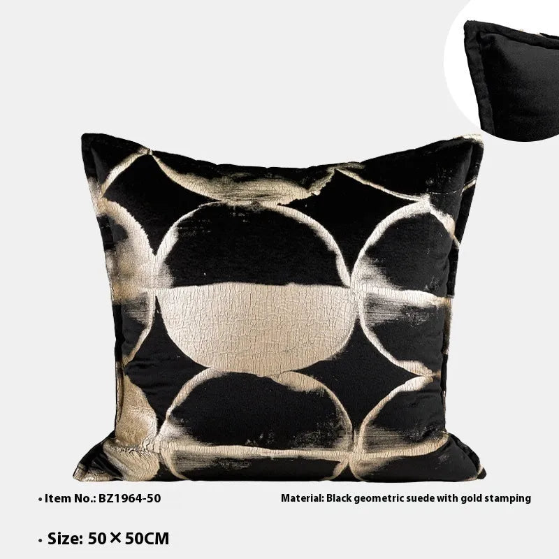Black and gold abstract patterned decorative flannel cushion on a grey sofa.