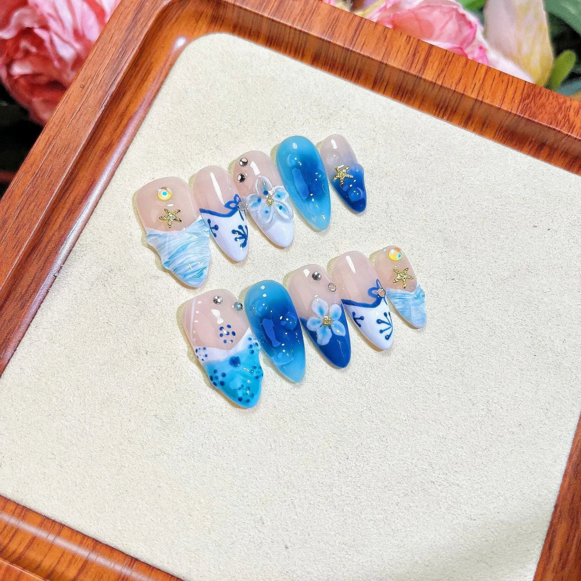 Set of blue transparent false nails with hand-painted carved design, showing sizes XS, S, M, L