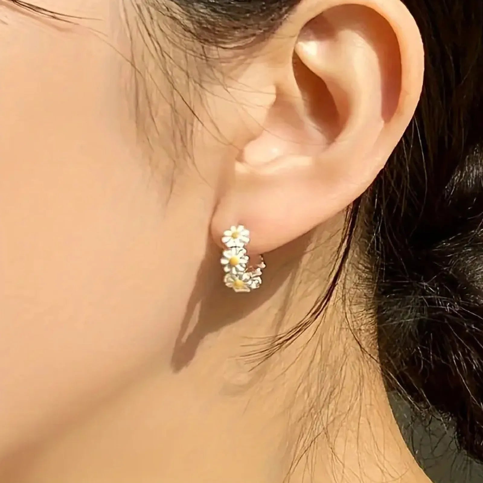 A pair of white daisy flower design ring earrings with a platinum-inlaid gemstone accent.