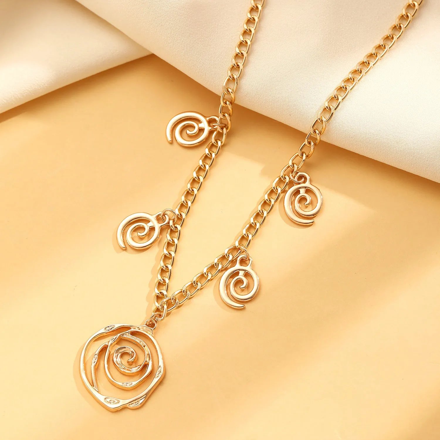 Women's spiral donut jewellery set showing matching gold necklace, bracelet, and earrings with geometric circle design