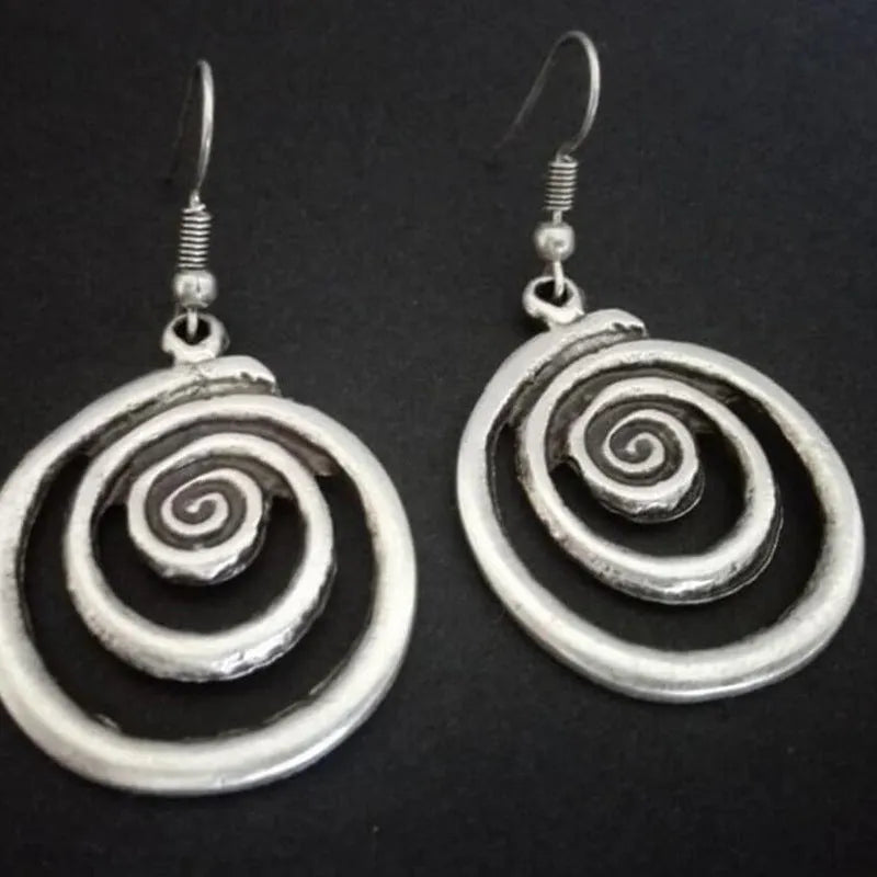 A pair of silver retro geometric spiral earrings with a distressed finish on a white background.