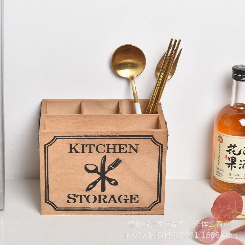 Open wooden kitchen storage box with internal grid holding knives, forks, and chopsticks.