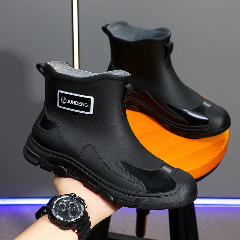 Pair of solid colour PVC rain boots with flat heel and low tube, round toe, visible sewing thread detail