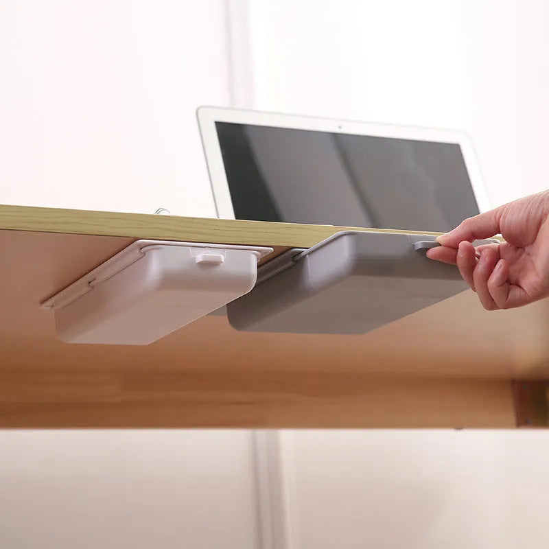 White plastic under-desk storage box with a lid open, showing an internal grid pattern.