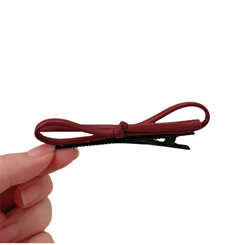 Wine red leather hair barrette with bow decoration shown from front and side views