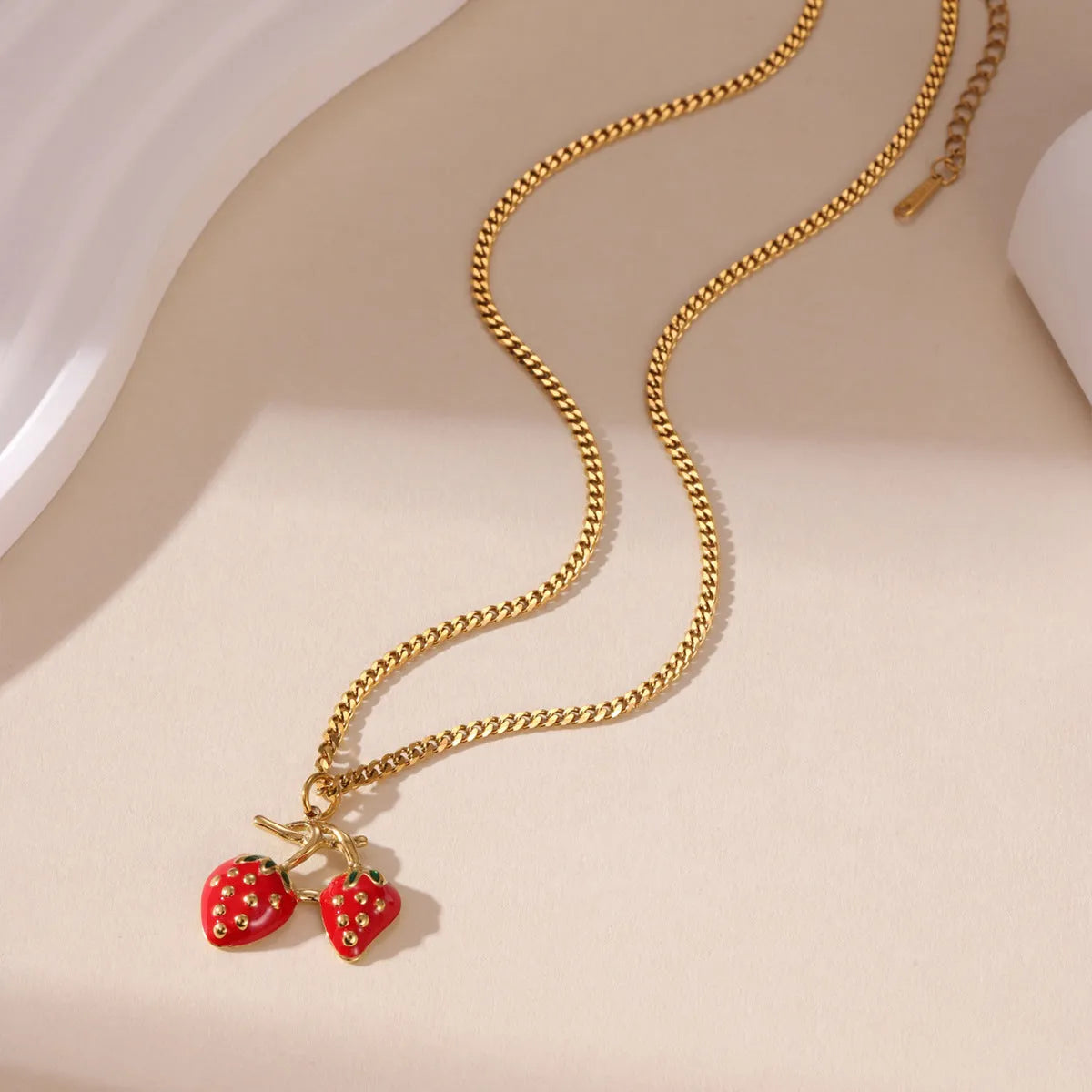 Close-up of a women's stainless steel strawberry pendant necklace on an alloy chain, showing red and white gradient colour options.