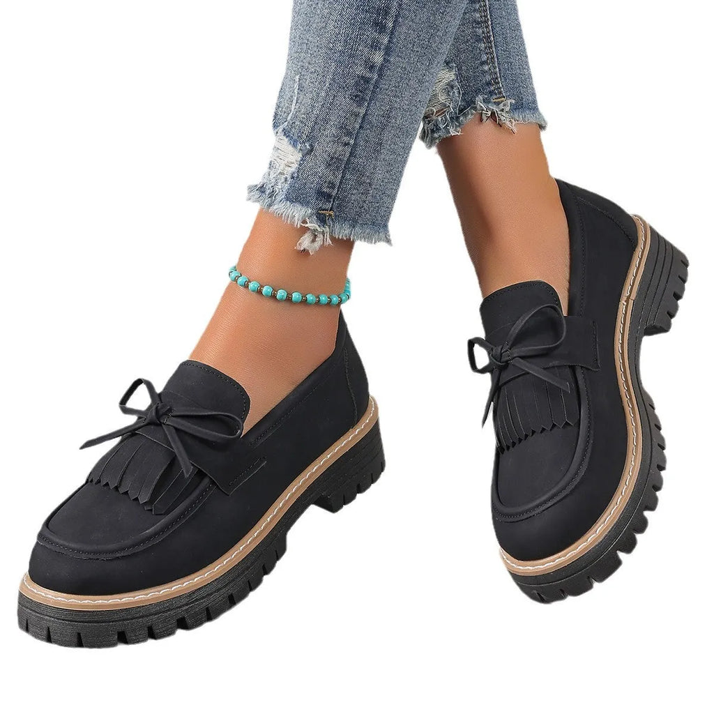Black plus size women's loafers with a tassel and bowknot detail on the front and a chunky rubber sole.