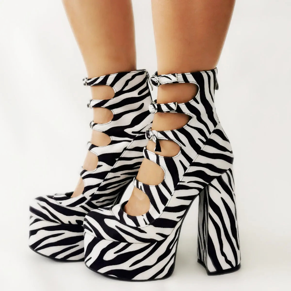 Women's black patent leather platform high heel boots with a serpentine belt ankle buckle.
