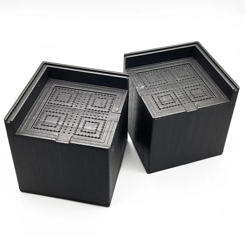 Four black thickened plastic bed foot mats arranged for height increasing furniture support