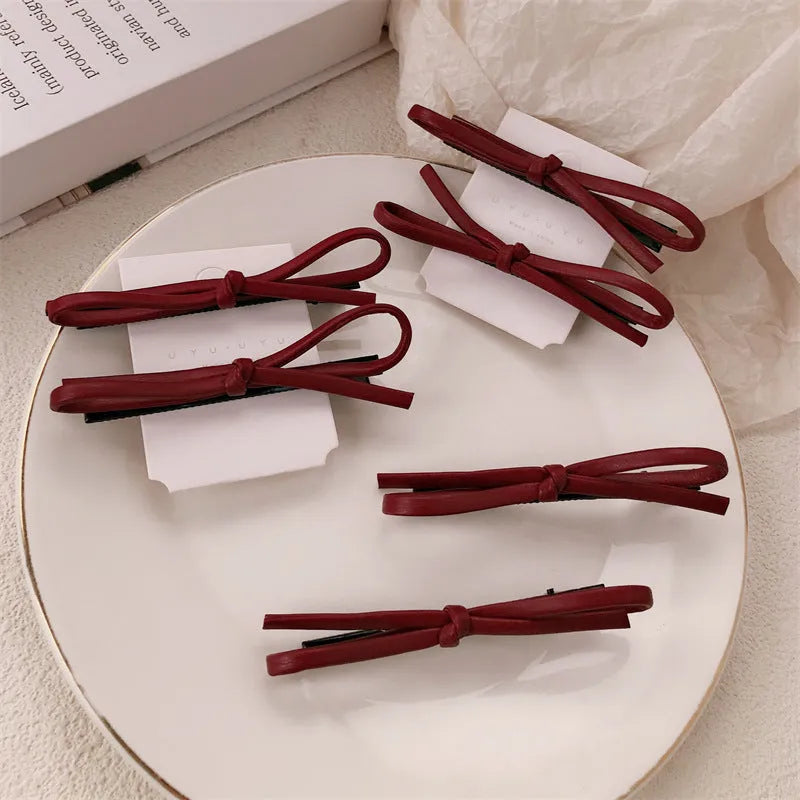 Wine red leather hair barrette with bow decoration shown from front and side views