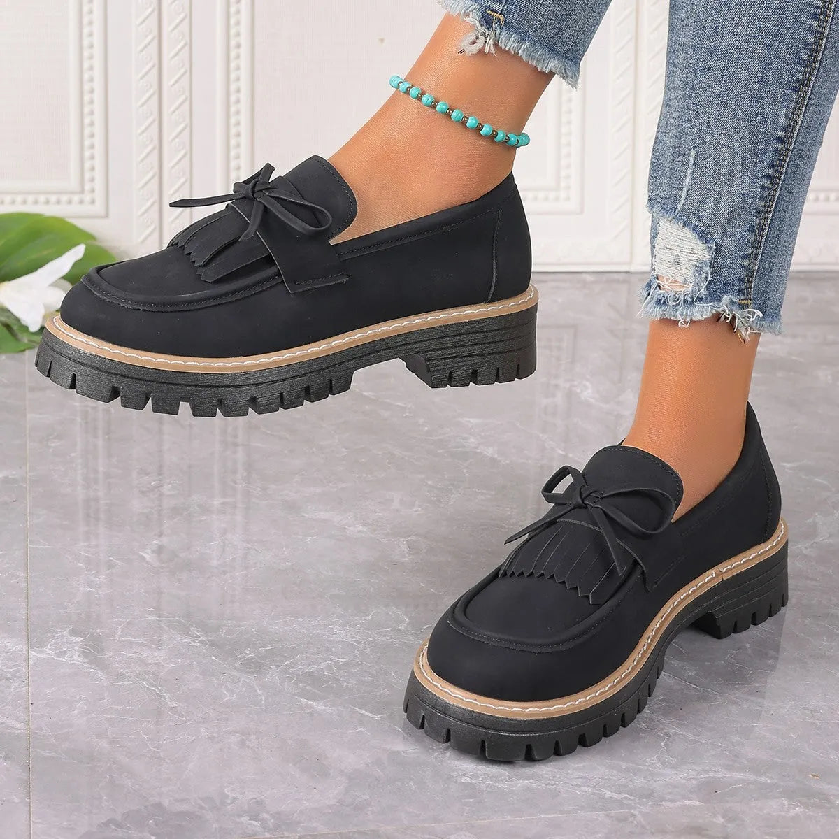 Black plus size women's loafers with a tassel and bowknot detail on the front and a chunky rubber sole.