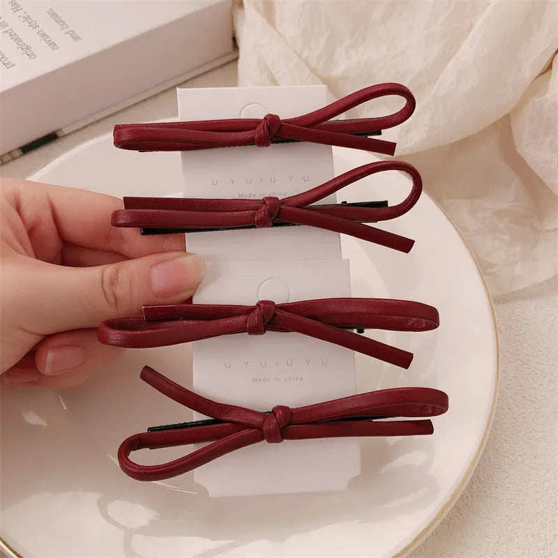 Wine red leather hair barrette with bow decoration shown from front and side views