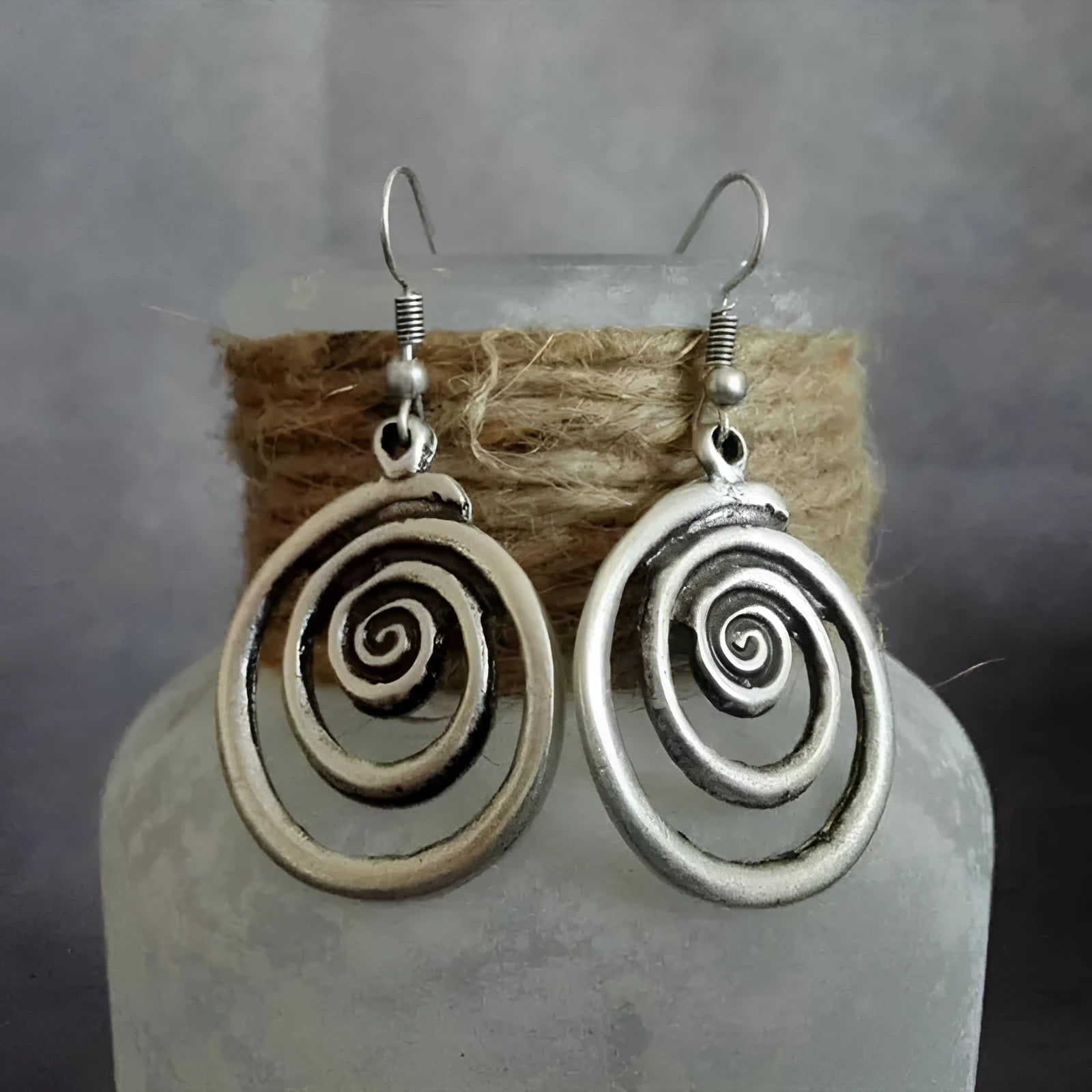 A pair of silver retro geometric spiral earrings with a distressed finish on a white background.