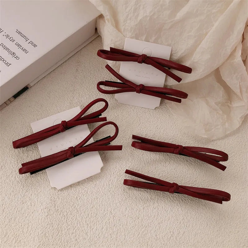 Wine red leather hair barrette with bow decoration shown from front and side views