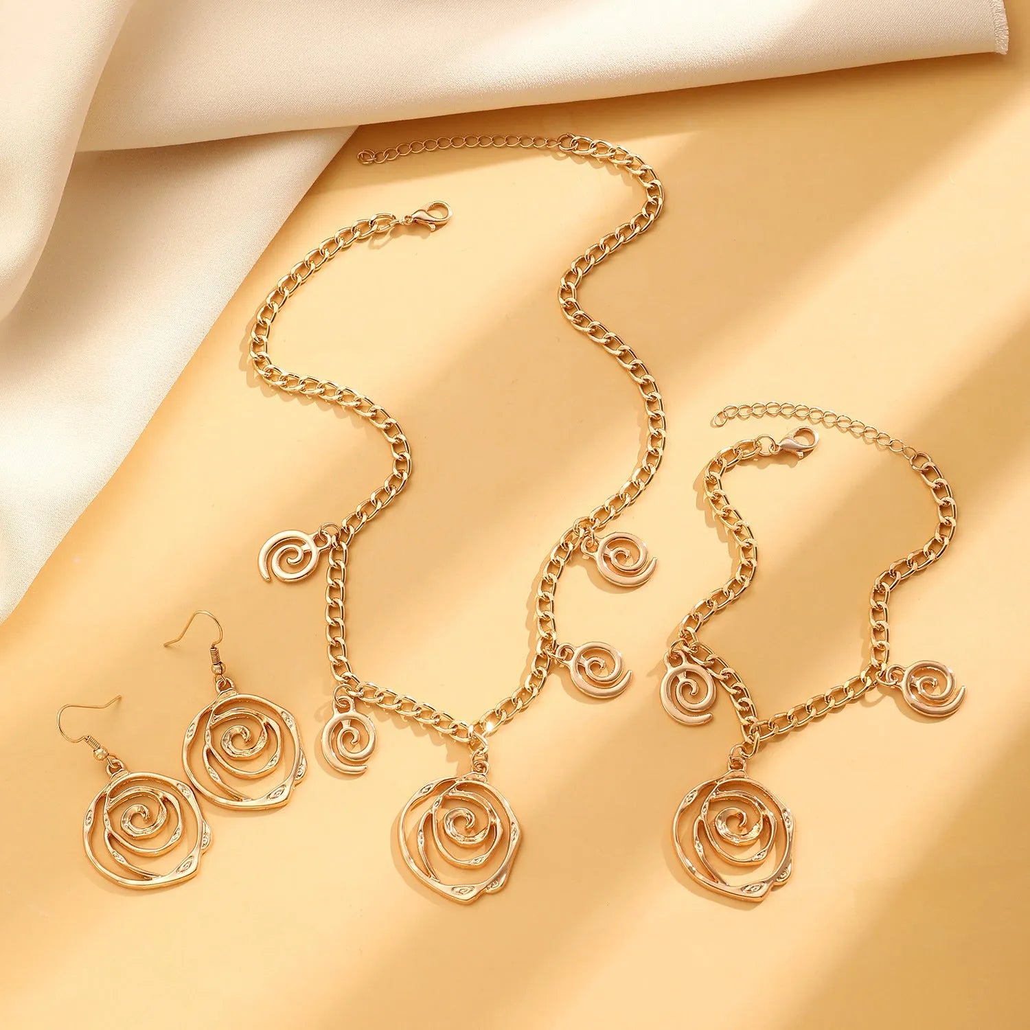 Women's spiral donut jewellery set showing matching gold necklace, bracelet, and earrings with geometric circle design