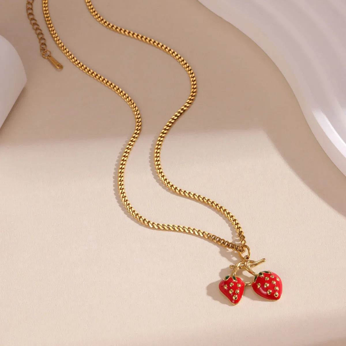 Close-up of a women's stainless steel strawberry pendant necklace on an alloy chain, showing red and white gradient colour options.