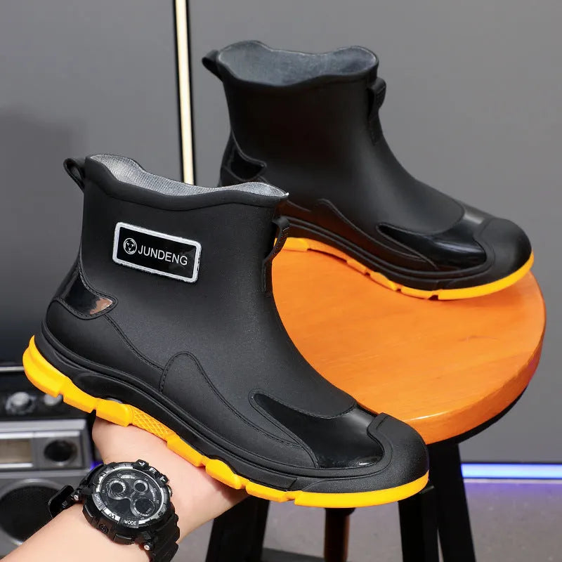 Pair of solid colour PVC rain boots with flat heel and low tube, round toe, visible sewing thread detail