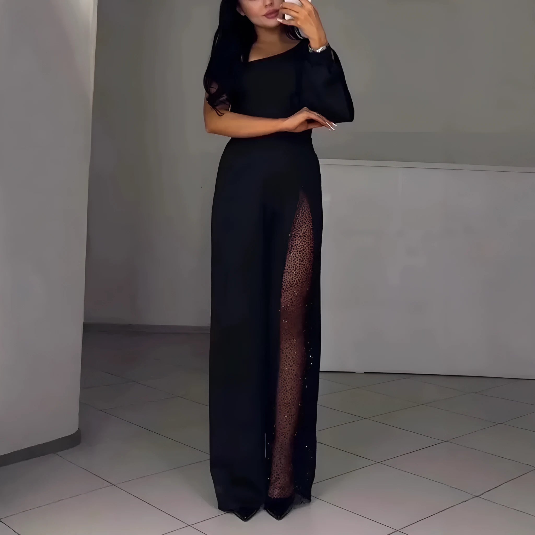 Black women's jumpsuit with an oblique shoulder neckline, long sleeves, a high leg slit, and a mid waist.