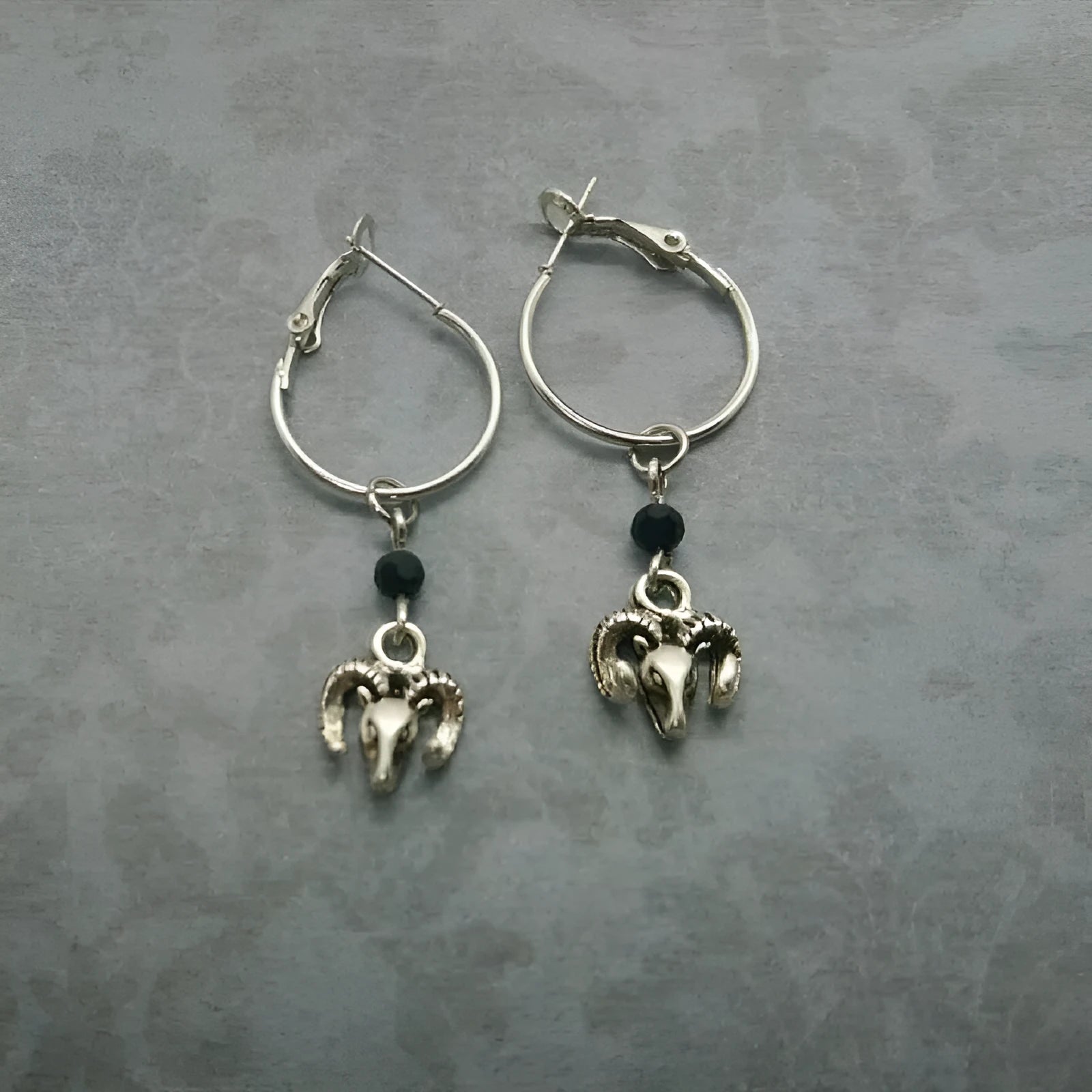 A pair of silver round ring earrings with a Tibetan antelope design.