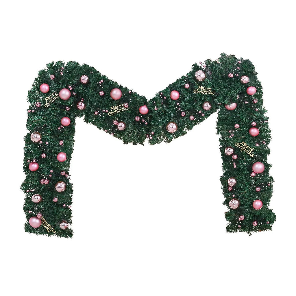Long pink rattan Christmas wreath with small fruit decoration, shown draped on a door.