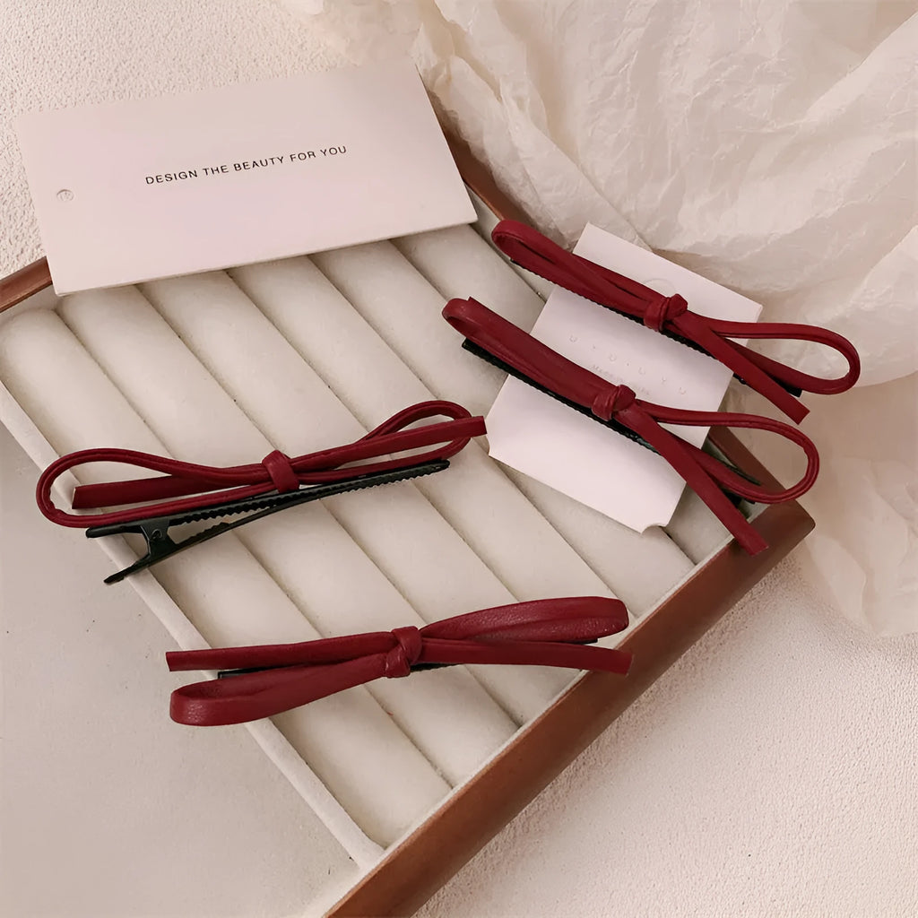 Wine red leather hair barrette with bow decoration shown from front and side views