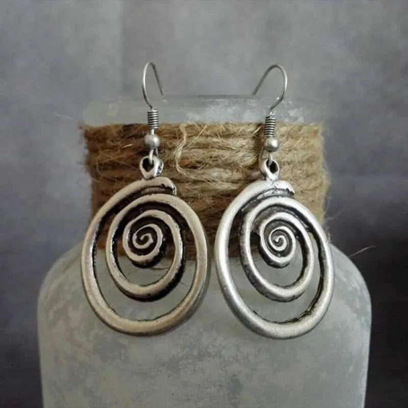 A pair of silver retro geometric spiral earrings with a distressed finish on a white background.