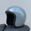 Retro-style open-face motorcycle helmet in glass fibre construction shown in a cement grey colour.