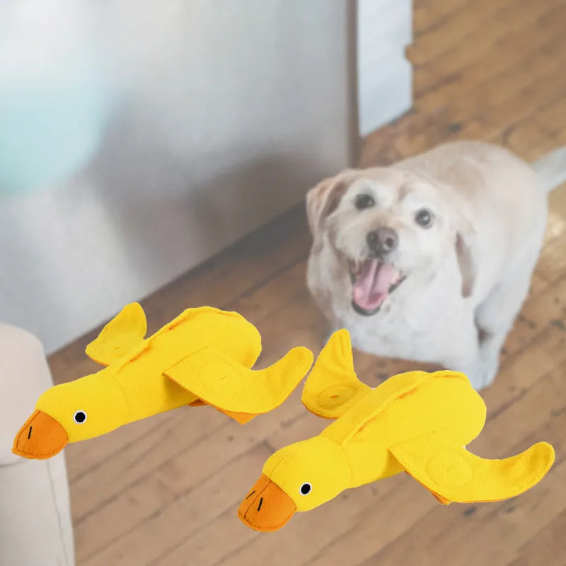 Yellow plush teddy dog toy with a attached duck doll and visible treat pockets on a white background.