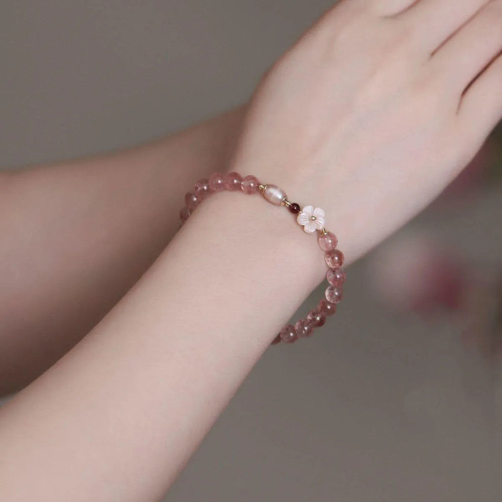 Women's strawberry quartz crystal bracelet with flower-shaped peach blossom design on wrist