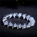 Close-up of a women's white crystal ghost pyramid bracelet with a Ruyi charm on a wrist.