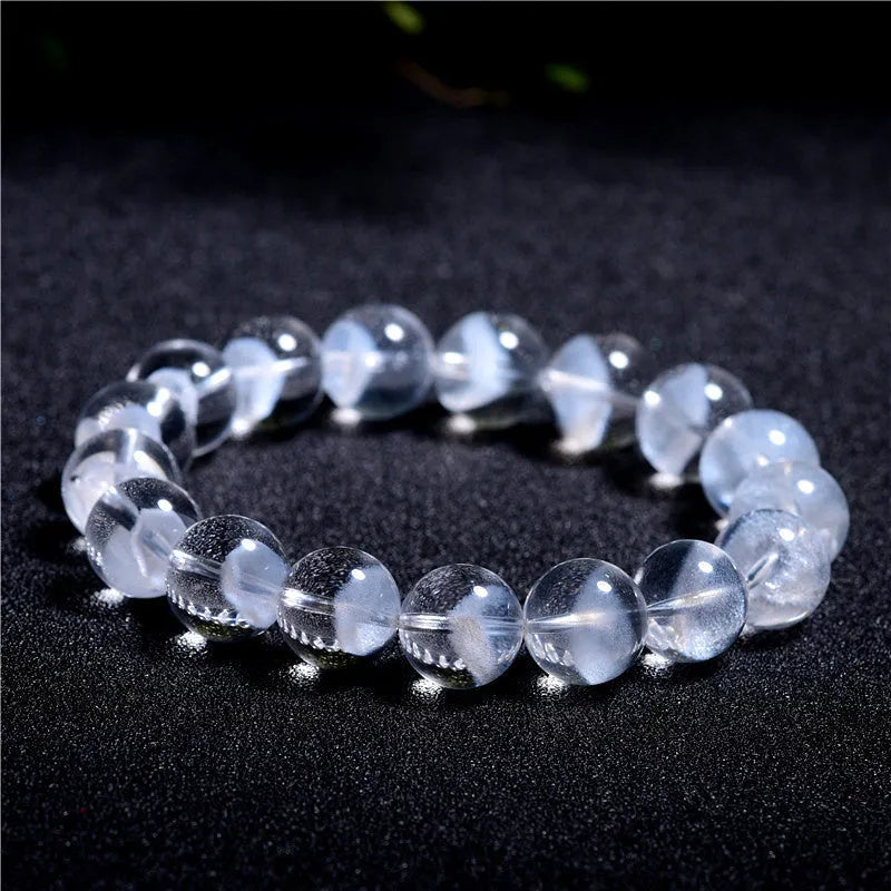 Close-up of a women's white crystal ghost pyramid bracelet with a Ruyi charm on a wrist.