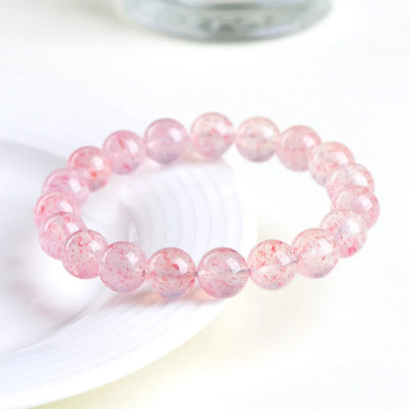 Strawberry quartz crystal bracelet with white geometric beads on a stretch band.