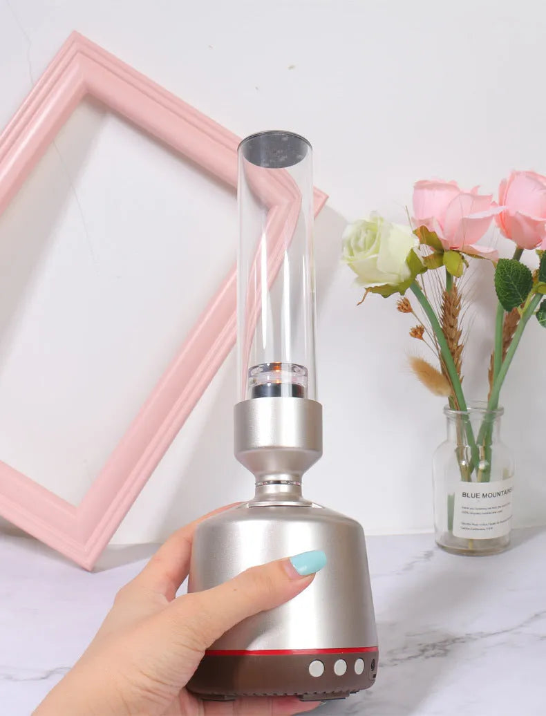 White silver Bluetooth speaker with integrated candlelight atmosphere night light on a table.