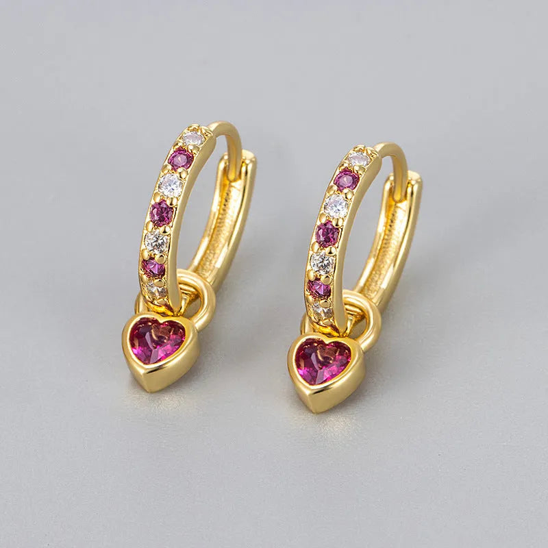 Women's heart-shaped clip-on earring with coloured gemstone centre on a gold-coloured metal setting.