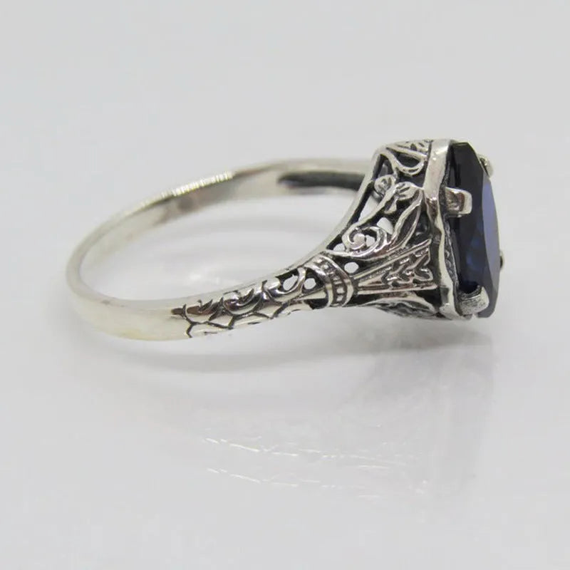 Women's silver alloy ring with geometric hollow design and central zircon stone, on a plain background