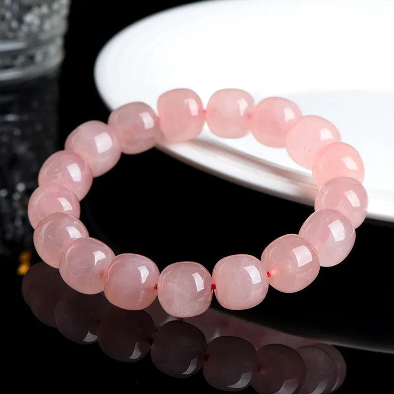 Pink natural crystal barrel bead bracelet with geometric shape on wrist.