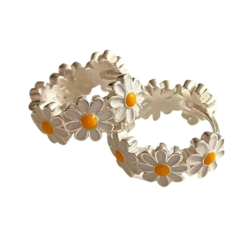 A pair of white daisy flower design ring earrings with a platinum-inlaid gemstone accent.