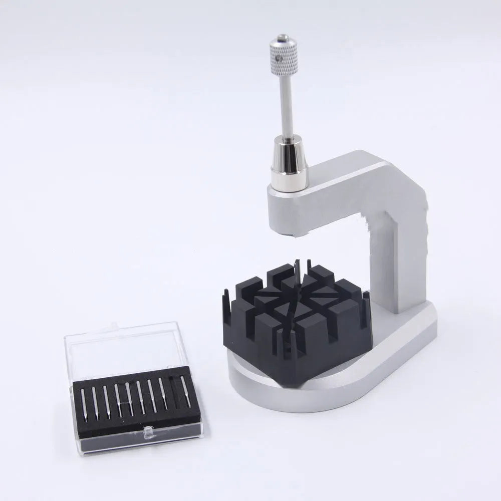 Silver multi-purpose press strap removal tool made from tool steel on a work surface.